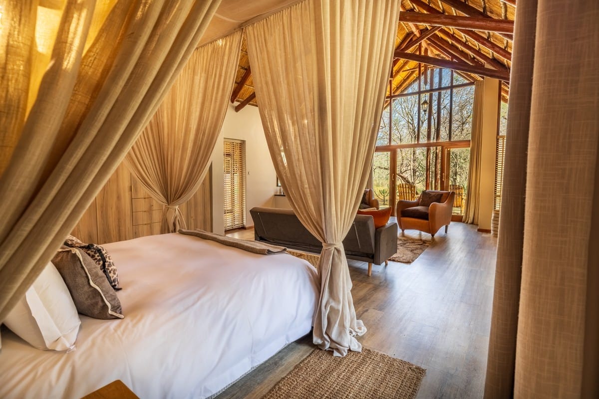 Kubu Suite bed draped in sheer curtains, sitting area beyond