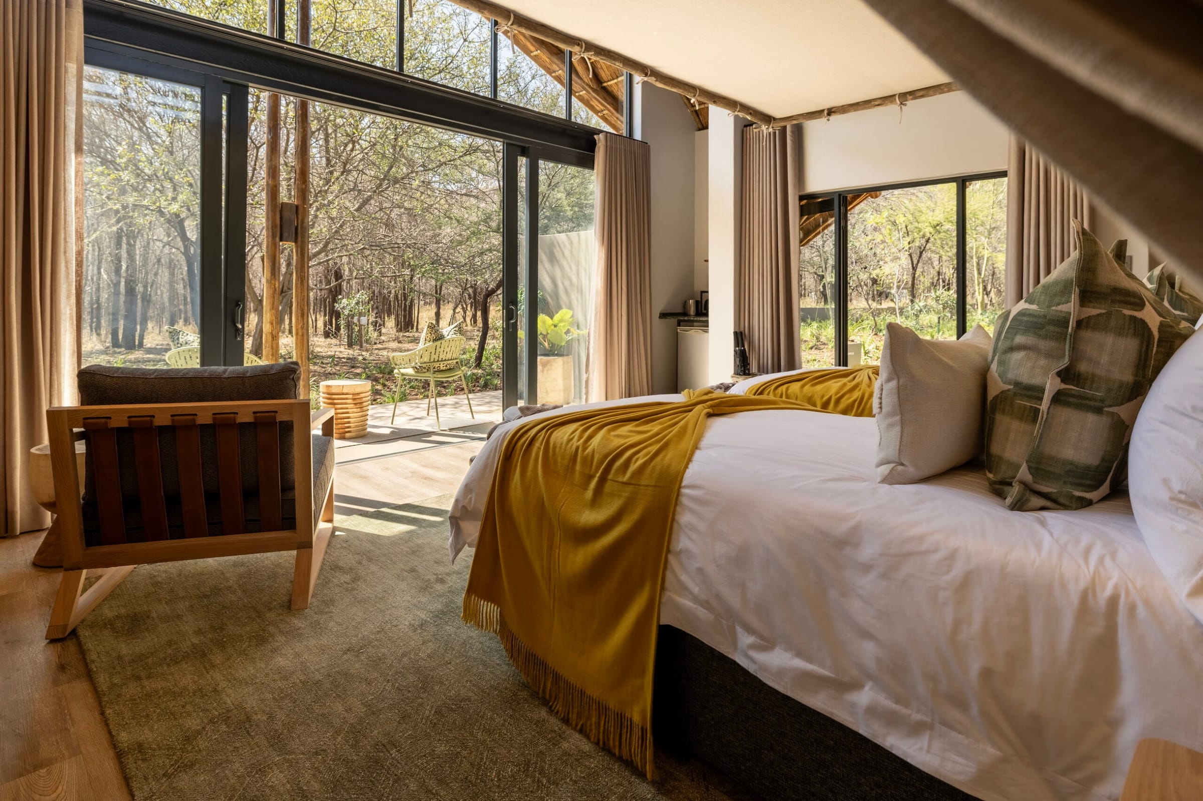 Suite bedroom with a yellow throw and glass doors open onto the patio